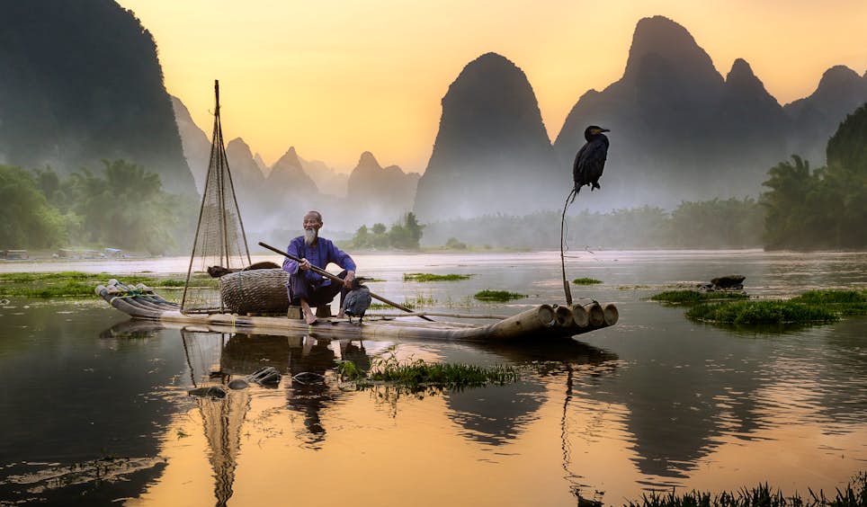 The ancient practice of cormorant fishing, where the bird catches fish too big to swallow, can still be witnessed in some parts of China © Pacmanfrog Photo / Moment RF / Getty Images