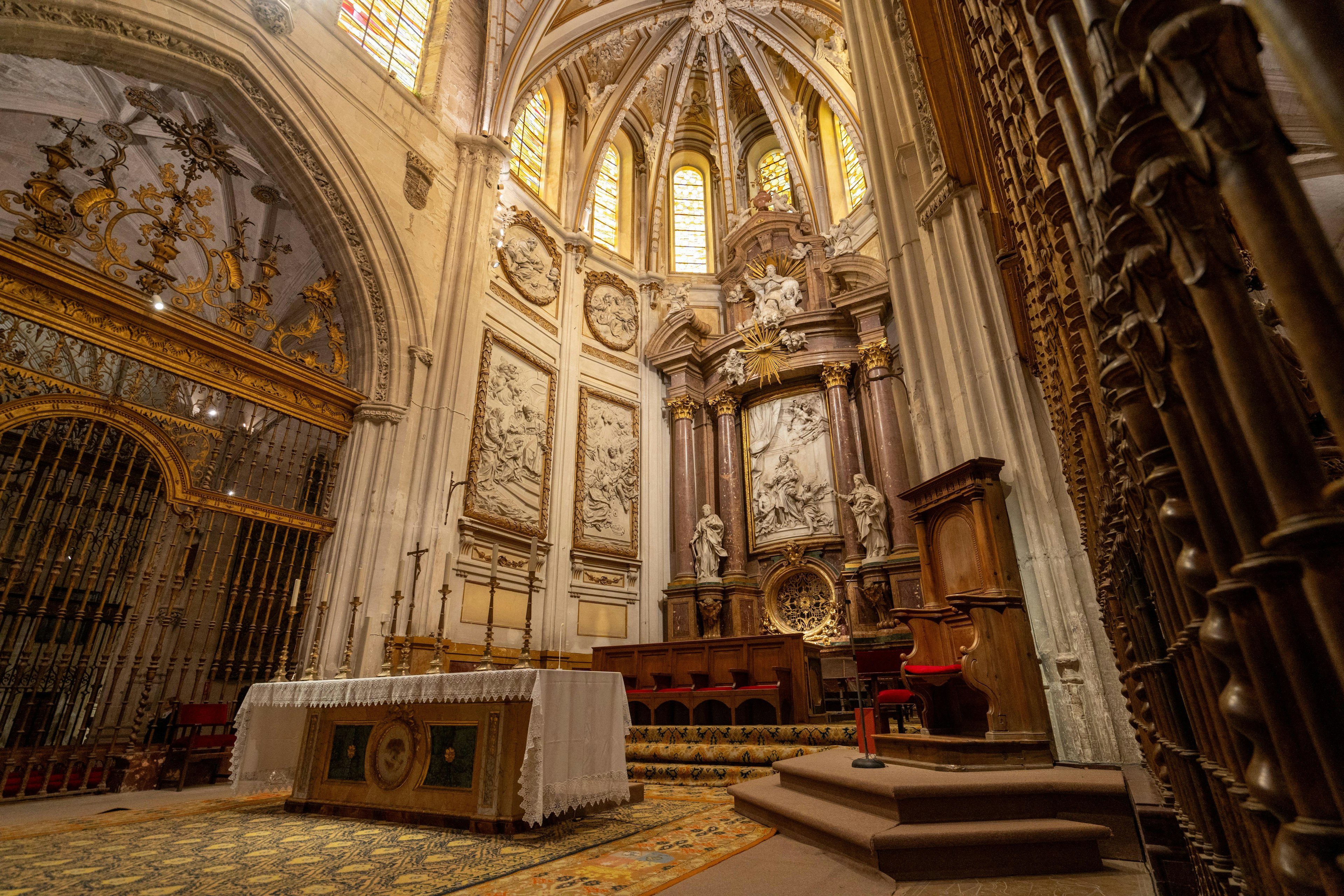 The cathedral's interior highlights Gothic vaulting, ornate altarpieces, and detailed stained glass windows.